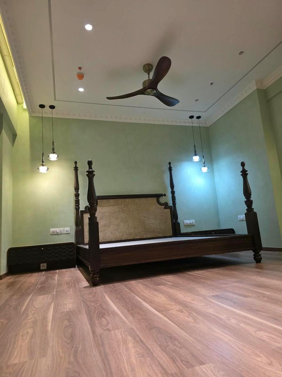 Bedroom with four-poster bed in dark wood and cane, pendant lights and wooden flooring