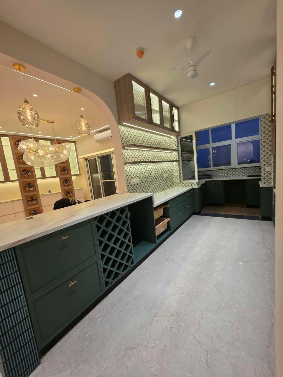 Green kitchen with wine rack, tiled backsplash and lit glass wall cabinets