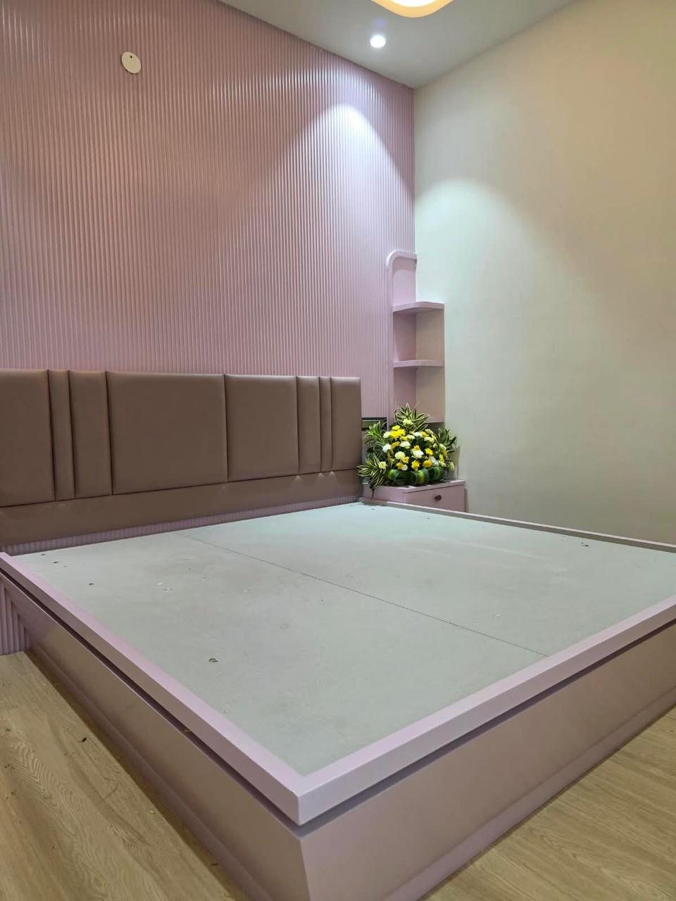 Bedroom in soft pink with fluted wall panels, channel headboard and corner shelves