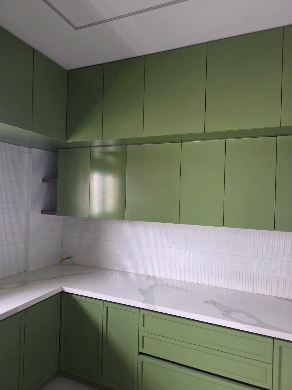 Sage-green kitchen with shaker base cabinets, quartz counter and fluted white tiles