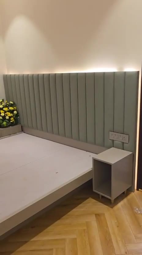 Bedroom with full-wall sage headboard, cove lighting and herringbone floor