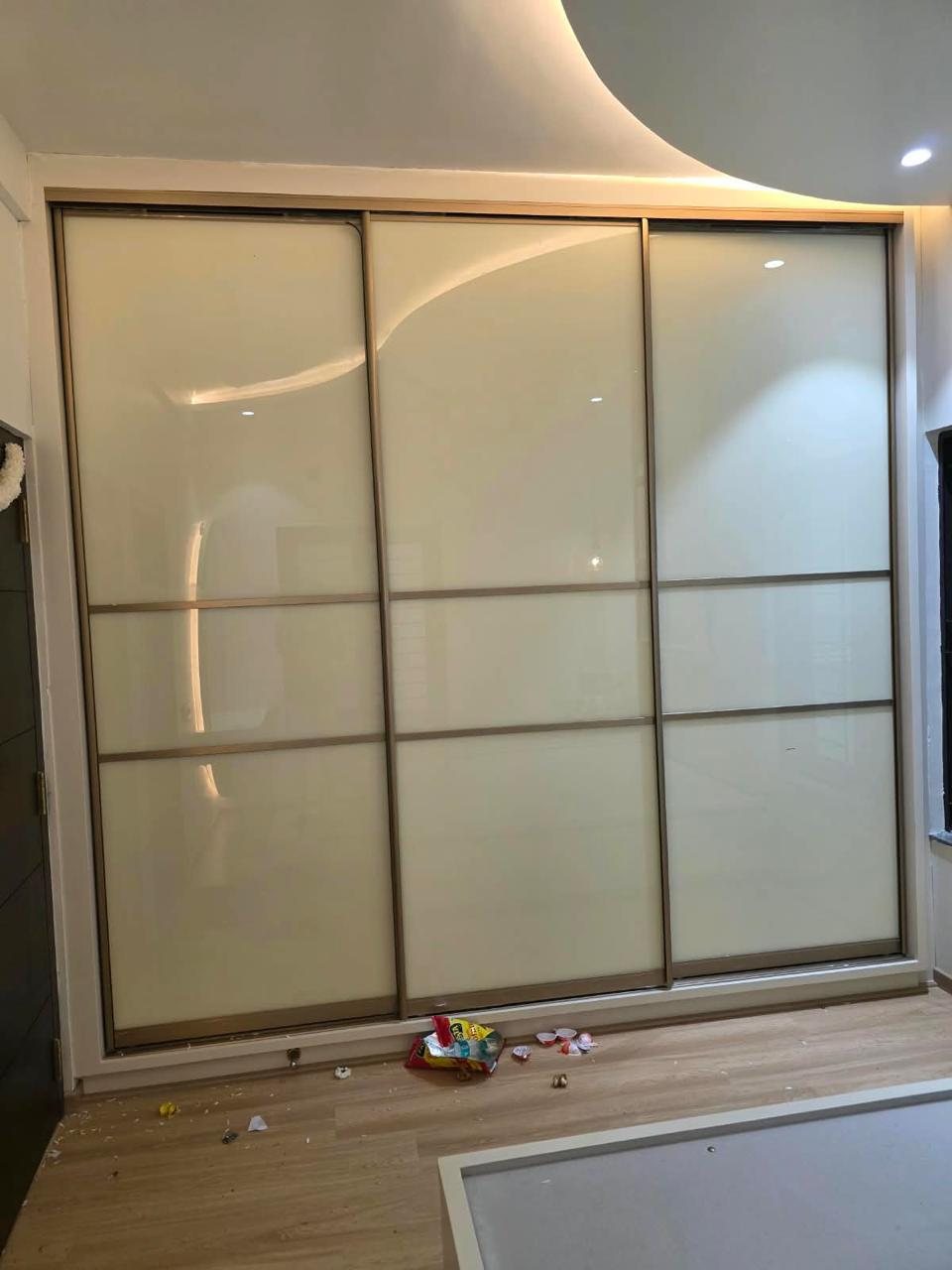 Three-door sliding wardrobe in lacquered glass with champagne frames